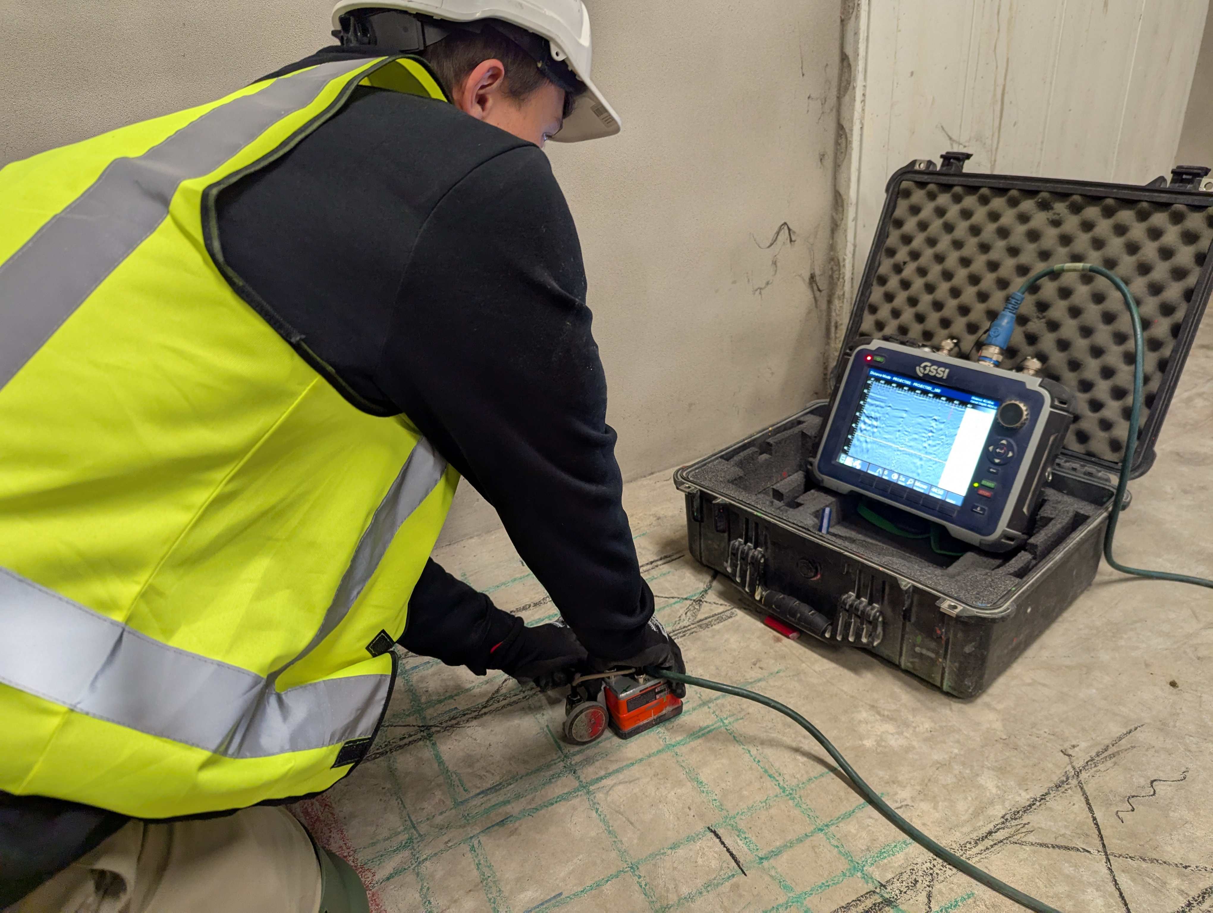 Professional technician using GPR equipment to scan a concrete slab